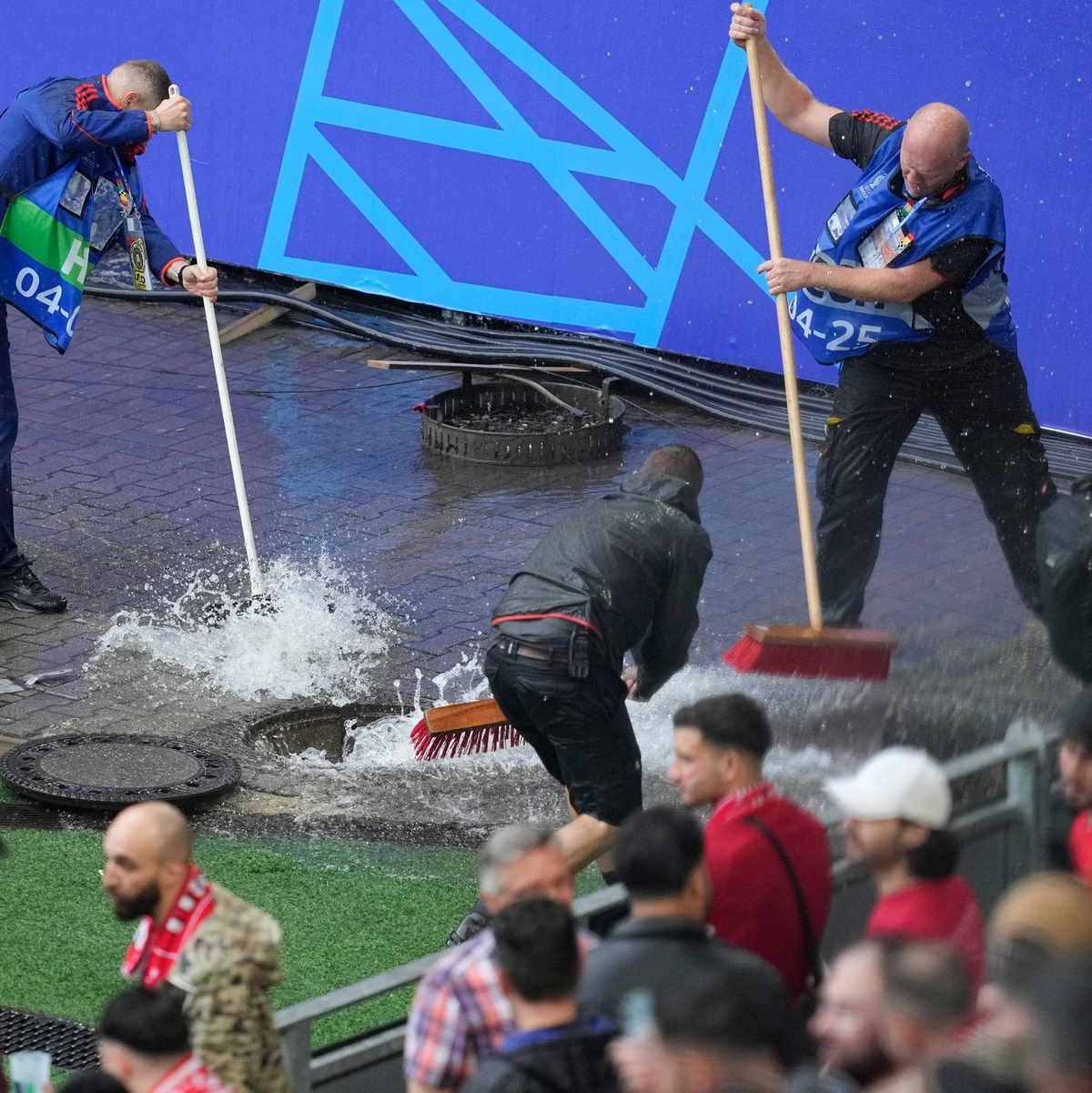 Kampf gegen die Wassermassen: Mitarbeiter sind vor dem Spiel Türkei gegen Georgien im Stadion im Einsatz. - Foto: Andreea Alexandru/AP