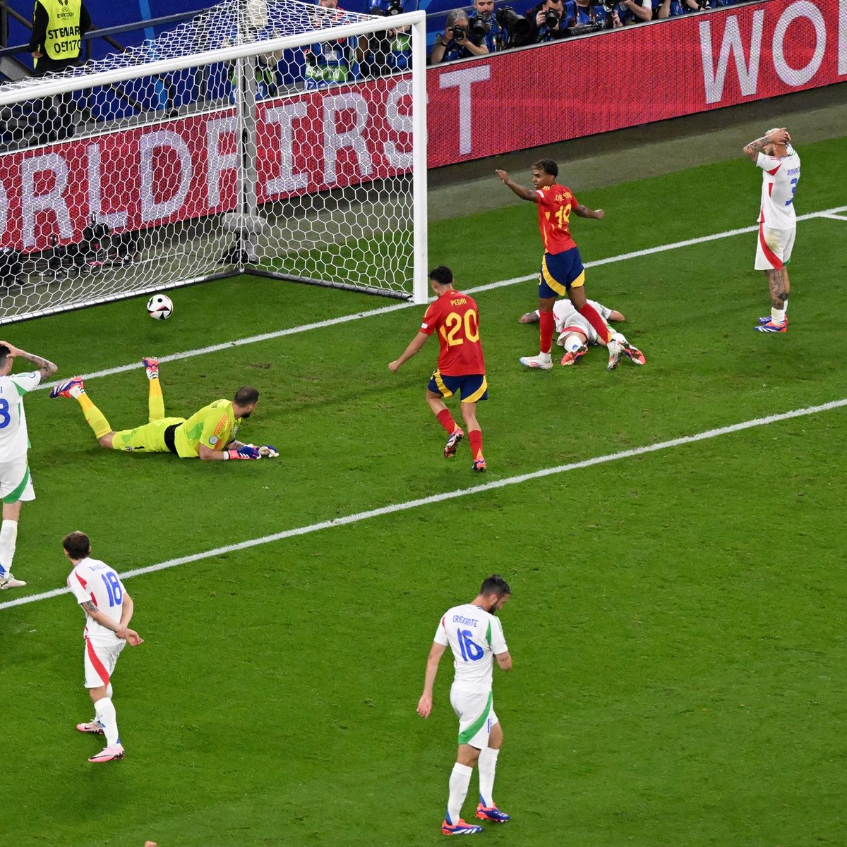 Italiens Torhüter Gianluigi Donnarumma liegt nach dem Gegentor am Boden. Die Spanier jubeln, während die Italiener enttäuscht auf dem Platz stehen. - Foto: Julian Stratenschulte/dpa