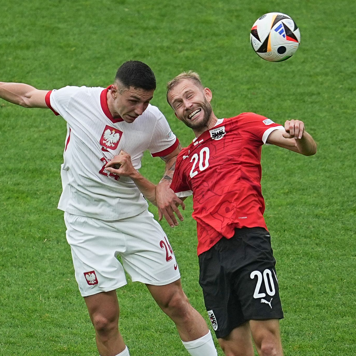 Polens Bartosz Slisz (l) im Kopfballduell mit dem Österreicher Konrad Laimer. - Foto: Michael Kappeler/dpa