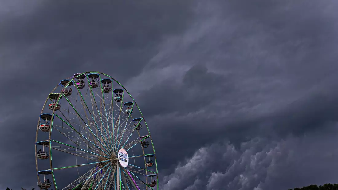 Dunkle Regenwolken ziehen über ein Riesenrad auf dem Gelände des Hurricane-Festivals in Scheeßel hinweg. - Bild: Moritz Frankenberg/dpa