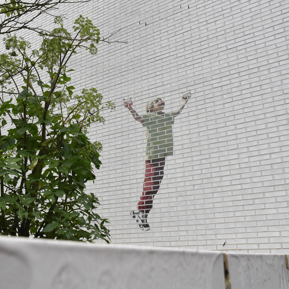 Ein Gedenkgarten soll an die getöteten Kinder erinnern. An einer Hauswand: Ein Kind, das einen Drachen steigen lässt. - Foto: Alina Grünky/dpa