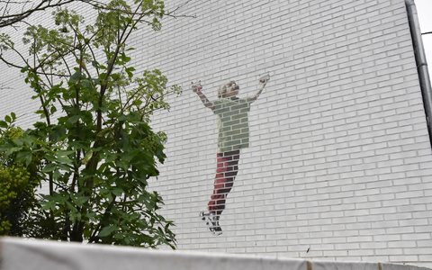 Ein Gedenkgarten soll an die getöteten Kinder erinnern. An einer Hauswand: Ein Kind, das einen Drachen steigen lässt. - Foto: Alina Grünky/dpa
