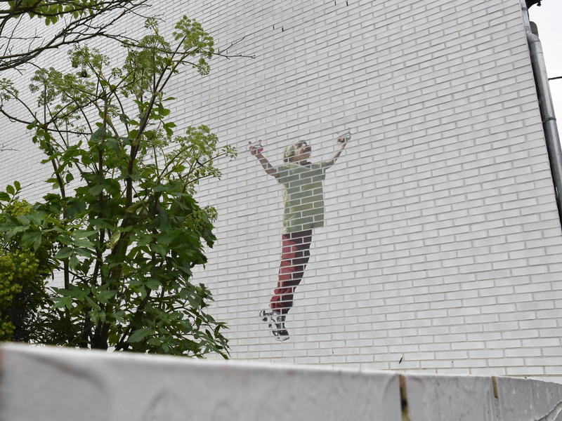 Ein Gedenkgarten soll an die getöteten Kinder erinnern. An einer Hauswand: Ein Kind, das einen Drachen steigen lässt. - Foto: Alina Grünky/dpa
