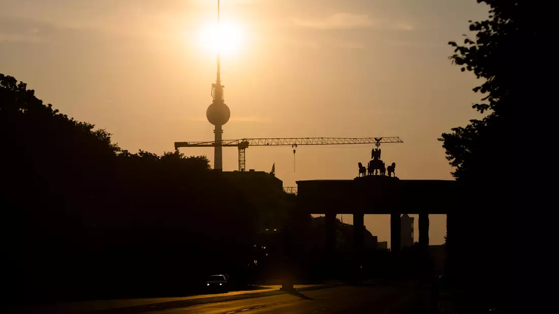 Das Brandenburger Tor und der Fernsehturm sind im Gegenlicht der aufgehenden Sonne zu sehen. Am Montag zeigt sich laut Vorhersage meist die Sonne, höchstens wird es locker bewölkt. - Bild: Christoph Soeder/dpa