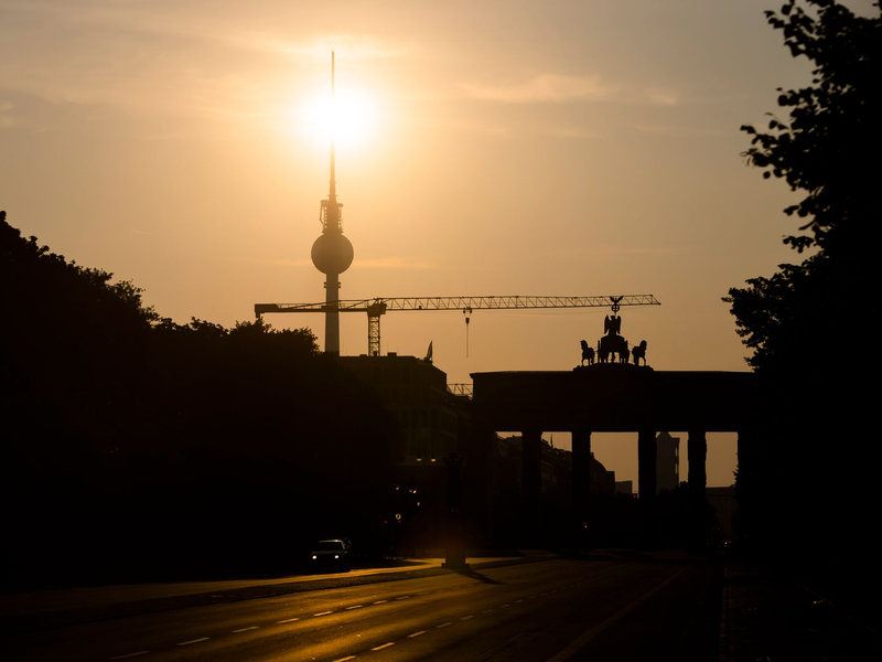 Das Brandenburger Tor und der Fernsehturm sind im Gegenlicht der aufgehenden Sonne zu sehen. Am Montag zeigt sich laut Vorhersage meist die Sonne, höchstens wird es locker bewölkt. - Foto: Christoph Soeder/dpa