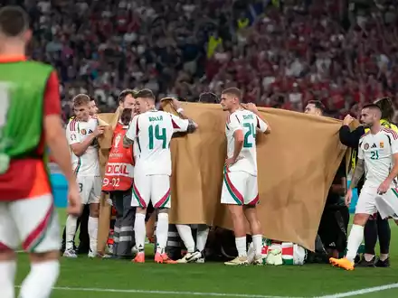 Die ungarischen Spieler halten einen Sichtschutz, während Stürmer Barnabas Varga behandelt wird. - Foto: Antonio Calanni/AP