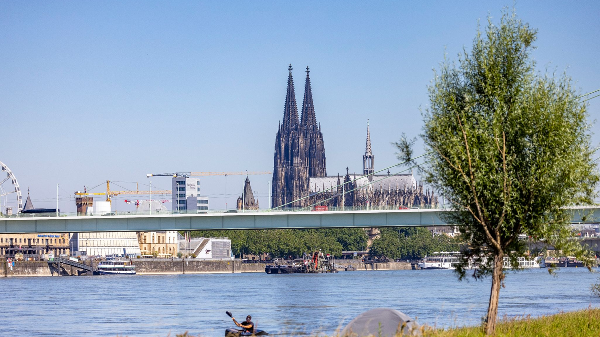 Ein Kajakfahrer rudert auf dem Rhein, im Hintergrund ist der Kölner Dom und die Severinbrücke zu sehen. - Foto: Thomas Banneyer/dpa