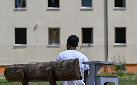 Ein Migrant sitzt auf einer Bank auf dem Gelände der Zentralen Erstaufnahmeeinrichtung für Asylbewerber des Landes Brandenburg in Eisenhüttenstadt. (Archivfoto) - Foto: Patrick Pleul/dpa