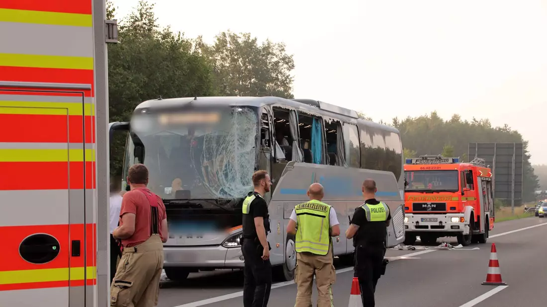 Rettungskräfte stehen neben dem beschädigten Reisebus auf der Autobahn 24. - Bild: SWM DV Studio
Ralf Drefin/dpa