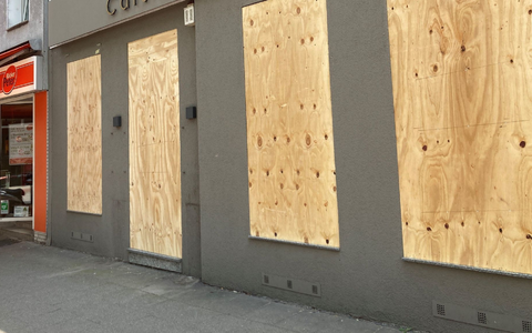 Ein Geschäft hat aus Sorge vor Ausschreitungen Bretter vor den Schaufenstern angebracht. - Foto: Marc Herwig/dpa Ein Geschäft hat aus Sorge vor Ausschreitungen Bretter vor den Schaufenstern angebracht. - Foto: Marc Herwig/dpa