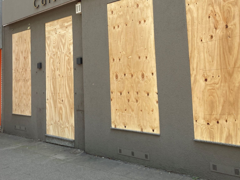 Ein Geschäft hat aus Sorge vor Ausschreitungen Bretter vor den Schaufenstern angebracht. - Foto: Marc Herwig/dpa