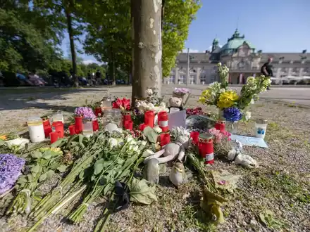 Blumen, Kerzen und handgeschriebene Trauerbekundungen stehen an einem Baum im Kurpark Bad Oeynhausen. Jetzt steht die Anklage. - Foto: Str/dpa