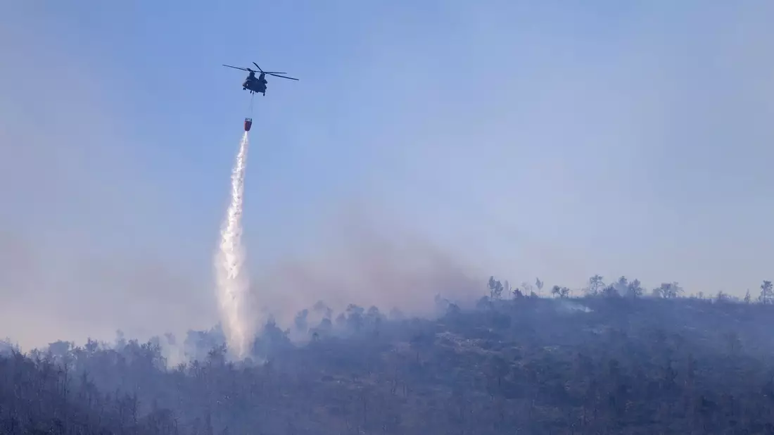 Ein Hubschrauber wirft Wasser auf einen Waldbrand im Norden Athens ab. - Bild: Yorgos Karahalis/AP