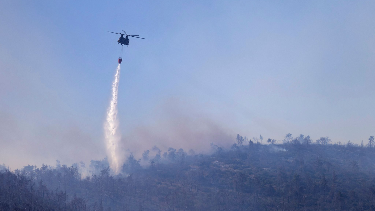 Ein Hubschrauber wirft Wasser auf einen Waldbrand im Norden Athens ab. - Foto: Yorgos Karahalis/AP