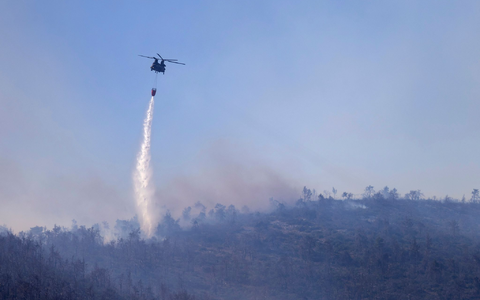 Ein Hubschrauber wirft Wasser auf einen Waldbrand im Norden Athens ab. - Foto: Yorgos Karahalis/AP