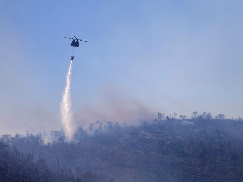 Ein Hubschrauber wirft Wasser auf einen Waldbrand im Norden Athens ab. - Foto: Yorgos Karahalis/AP