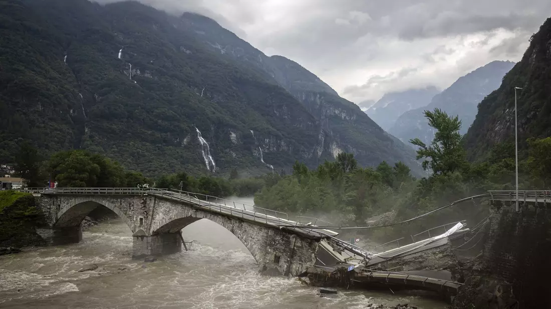 Eine Brücke im Maggiatal wird durch einen reißenden Fluss zerstört. - Bild: Michael Buholzer/KEYSTONE/dpa