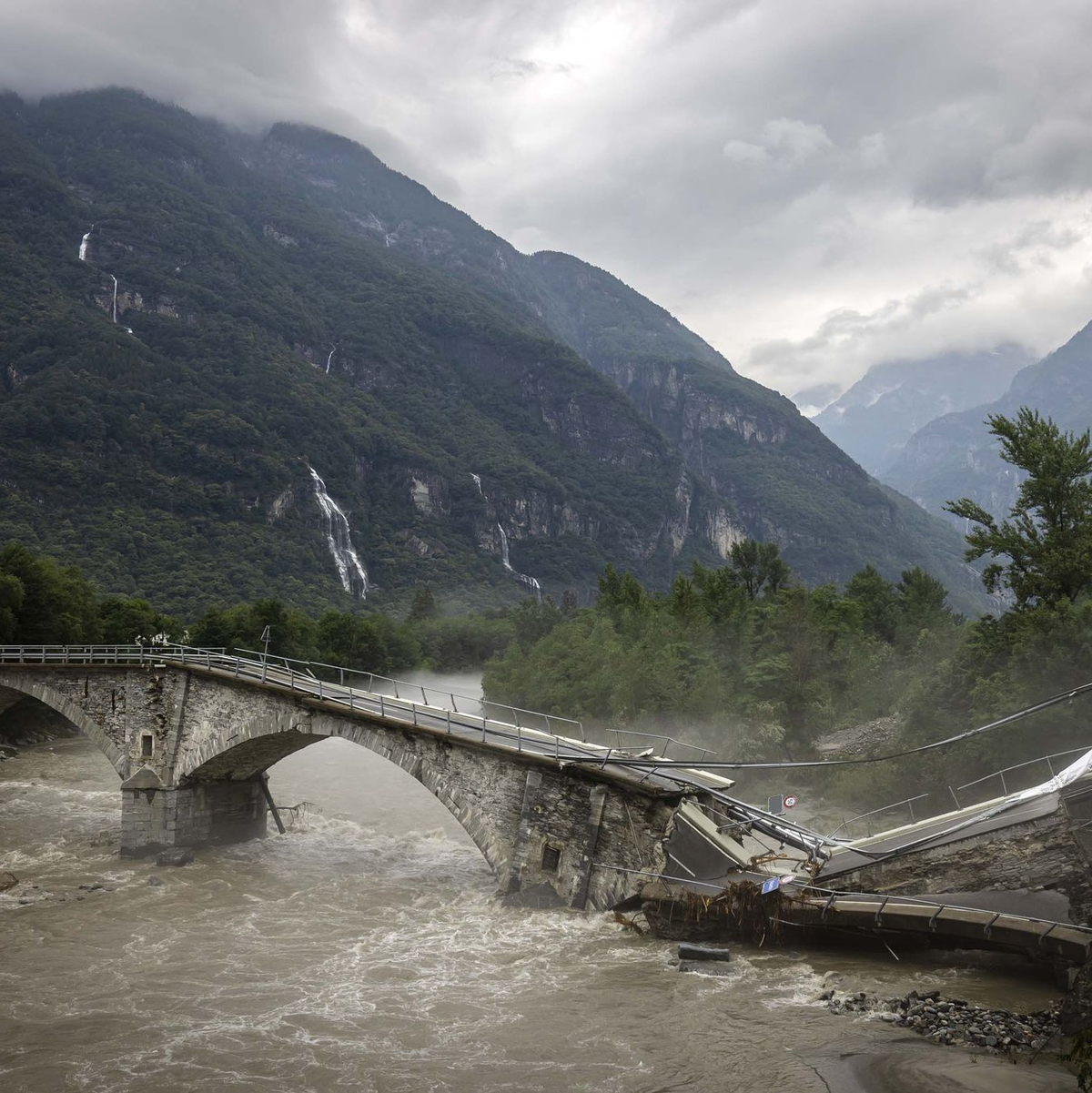 Eine Brücke im Maggiatal wird durch einen reißenden Fluss zerstört. - Foto: Michael Buholzer/KEYSTONE/dpa