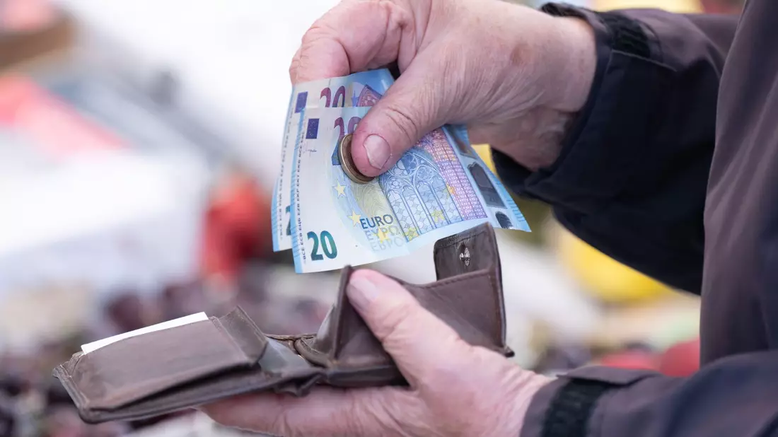 Eine Frau sortiert auf einem Wochenmarkt das Wechselgeld für ihre Einkäufe in ein Portemonnaie. - Bild: Sebastian Kahnert/dpa