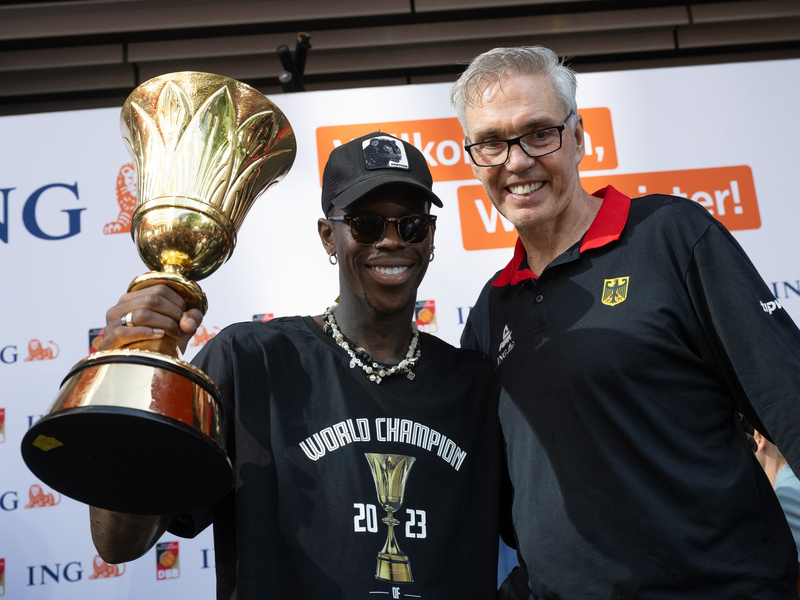 Bundestrainer Gordon Herbert (r) und sein KapitÀn Dennis Schröder mit dem WM-Pokal. - Foto: Boris Roessler/dpa