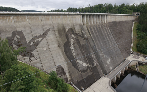 Auf der Staumauer der größten Trinkwassertalsperre Deutschlands wird mit Hochdruckreinigern ein Kunstwerk gemalt.  - Foto: Matthias Bein/dpa