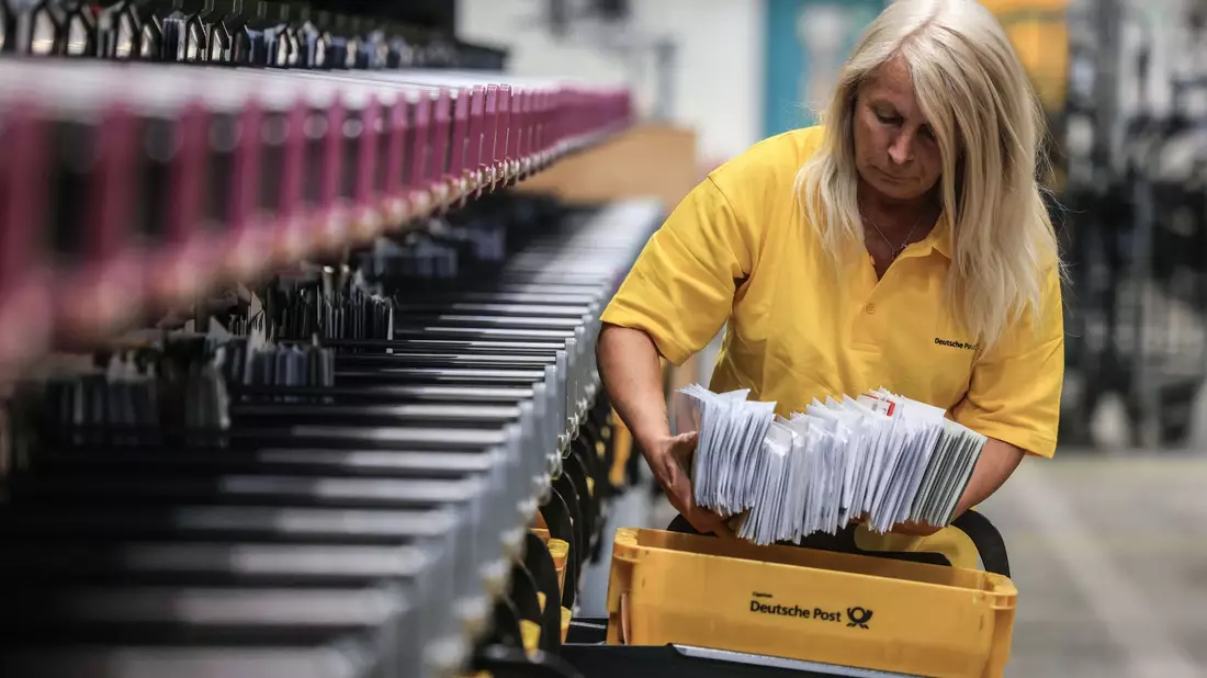 Eine Mitarbeiterin der Deutschen Post sortiert Briefe in einem Briefverteilzentrum. - Bild: Oliver Berg/dpa