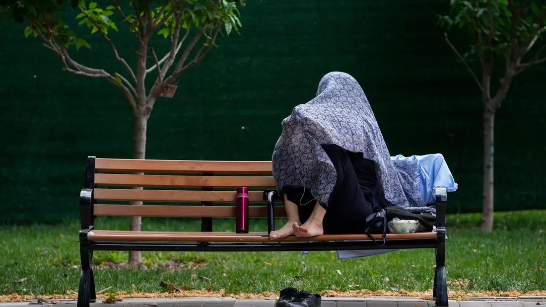 Eine Frau in China schützt sich mit einem Tuch vor der Sonne. - Bild: Andy Wong/AP