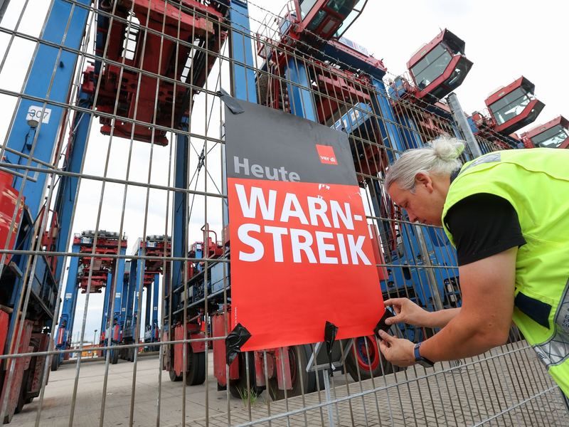 Ein Streikender hängt ein Plakat am Hamburger Hafen auf. (Archivfoto) - Foto: Bodo Marks/dpa