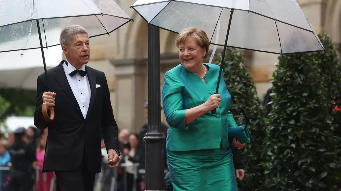 Im letzten Jahr mussten sich Angela Merkel und Ehemann Joachim Sauer auf den Weg ins Bayreuther Festspielhaus mit Regenschirmen schützen. (Archivfoto)  - Bild: Karl-Josef Hildenbrand/dpa