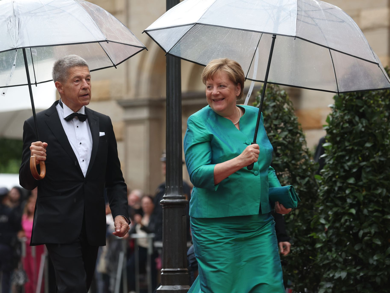 Im letzten Jahr mussten sich Angela Merkel und Ehemann Joachim Sauer auf den Weg ins Bayreuther Festspielhaus mit Regenschirmen schützen. (Archivfoto)  - Foto: Karl-Josef Hildenbrand/dpa