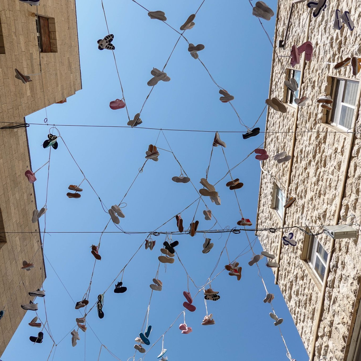 120 Paar Schuhe, als Installation in der Jerusalemer Innenstadt aufgehängt, erinnern an das Los der israelischen Geiseln in der Gewalt der Hamas.  - Foto: Nir Alon/ZUMA Press Wire/dpa
