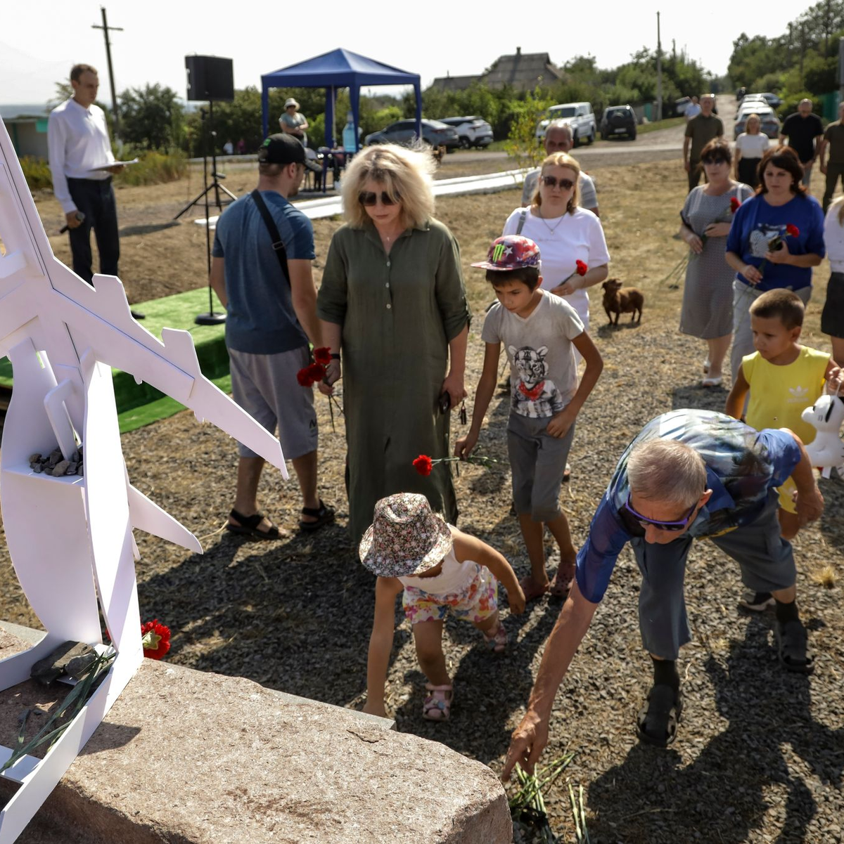 Menschen gedenken der Opfer an der Absturzstelle bei Hrabowe in der Ostukraine. - Foto: Uncredited/AP/dpa