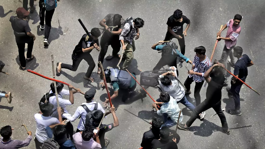 Studenten schlagen einen Polizisten mit Stöcken - Bild: Anik Rahman/AP/dpa