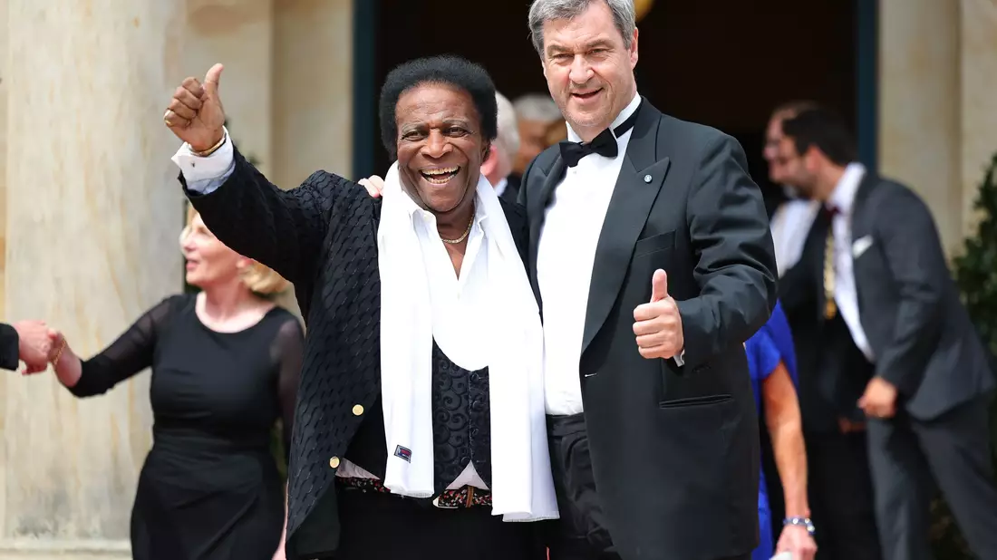 Markus Söder, Ministerpräsident von Bayern, und seine Frau Karin Baumüller-Söder, stehen zusammen mit Reiner Haseloff (CDU), Ministerpräsident von Sachsen-Anhalt, und seiner Frau Gabriele vor dem Bayreuther Festspielhaus. - Bild: Daniel Karmann/dpa