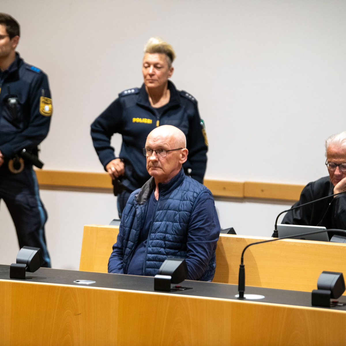 Der wegen der Ermordung von drei Nachbarn angeklagte Mann wird im Gerichtssaal von Polizisten bewacht. Der Mann will nach Angaben seines Anwalts auf Bildern nicht unkenntlich gemacht werden. (Archivfoto) - Foto: Stefan Puchner/dpa