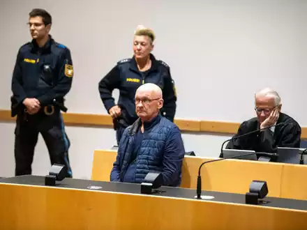 Der wegen der Ermordung von drei Nachbarn angeklagte Mann wird im Gerichtssaal von Polizisten bewacht. Der Mann will nach Angaben seines Anwalts auf Bildern nicht unkenntlich gemacht werden. (Archivfoto) - Foto: Stefan Puchner/dpa