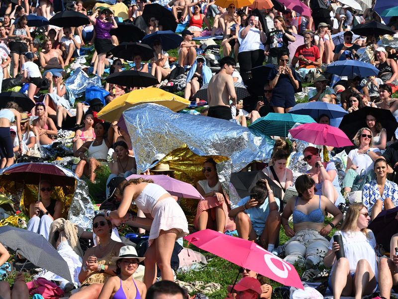 Mit Schirmen versuchten viele Fans, sich vor der Sonne zu schützen. - Foto: Felix Hörhager/dpa