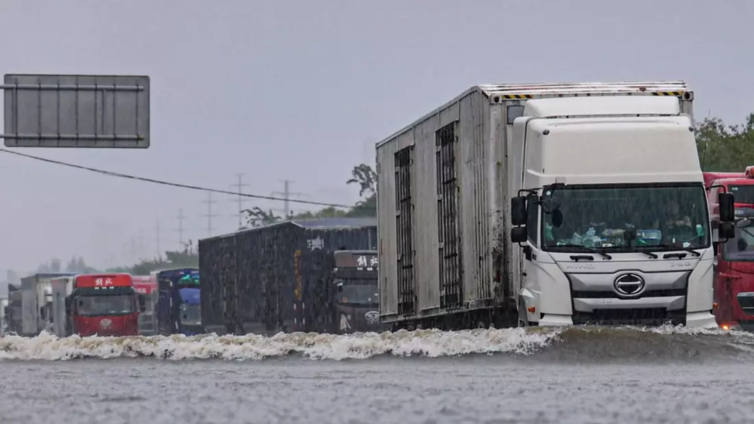 Große Lastwagen fahren durch ein Hochwasser in Shenyang in der nordostchinesischen Provinz Liaoning. - Bild: Wang Hongtao/Xinhua/AP
