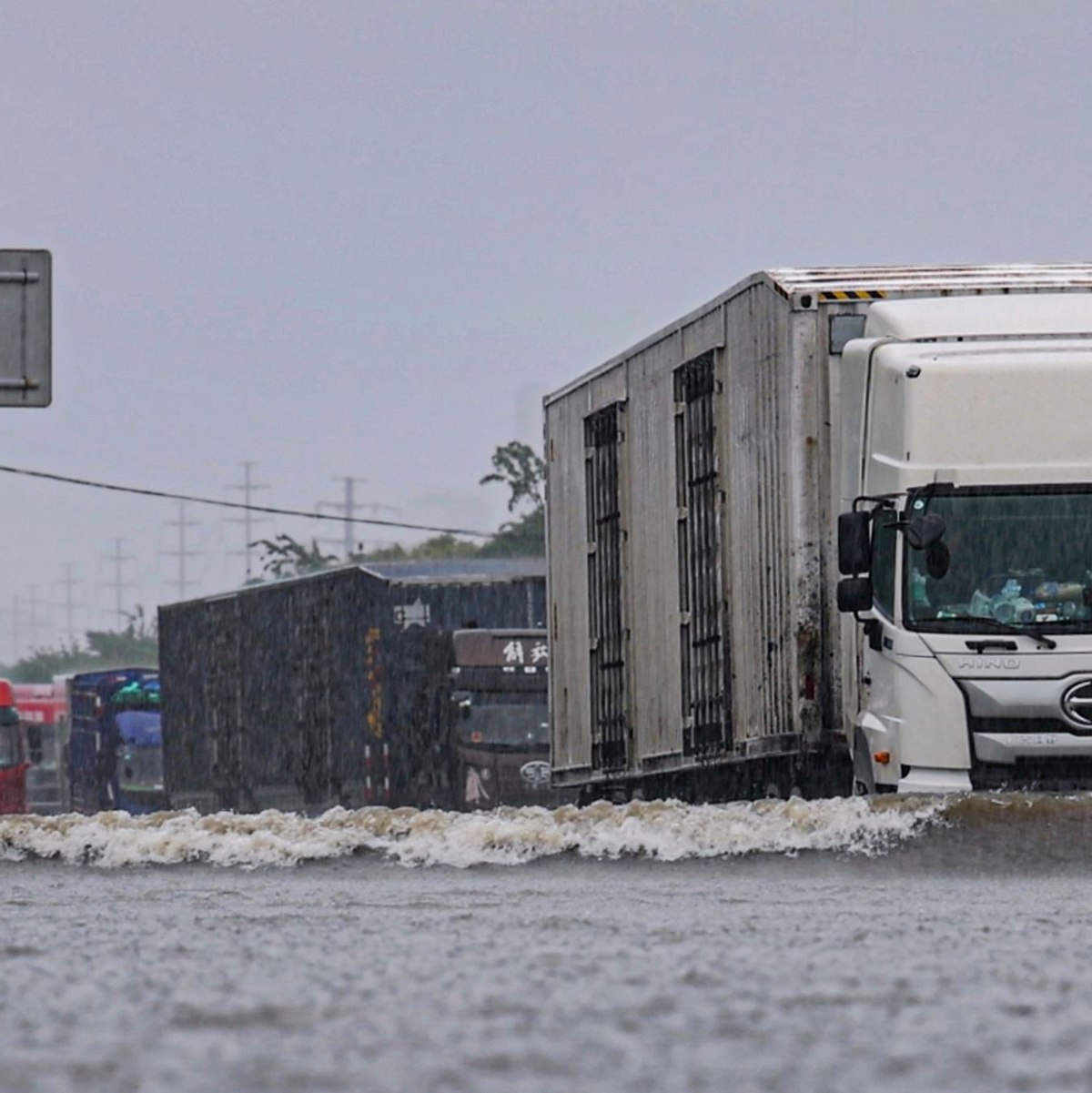 Große Lastwagen fahren durch ein Hochwasser in Shenyang in der nordostchinesischen Provinz Liaoning. - Foto: Wang Hongtao/Xinhua/AP