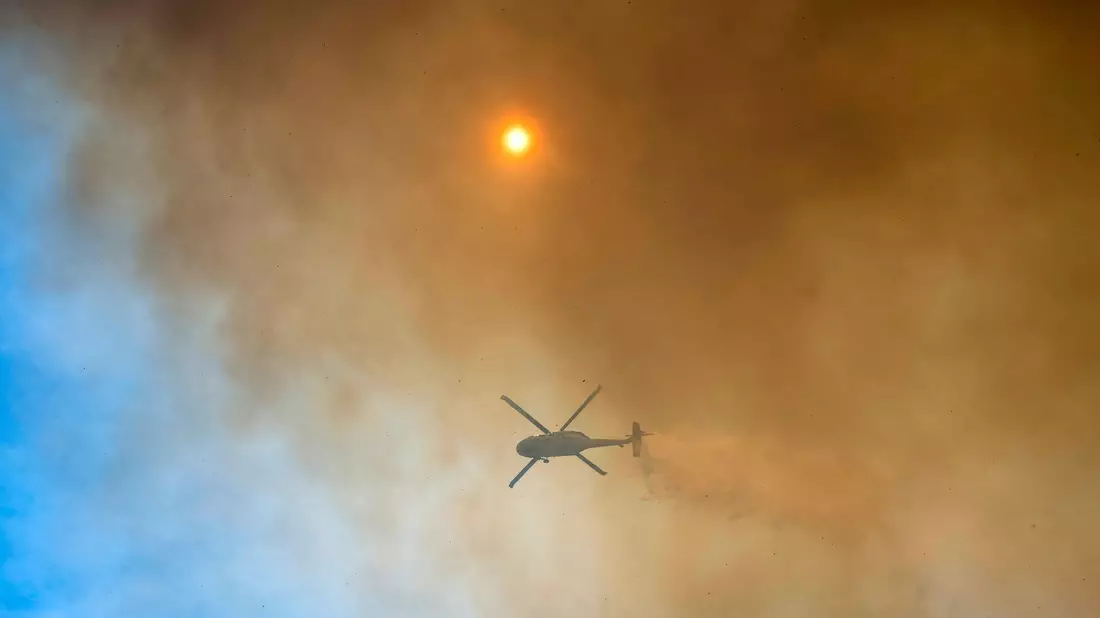 Mit Hubschraubern wird versucht, dem Feuer Herr zu werden.  - Bild: Nic Coury/AP/dpa