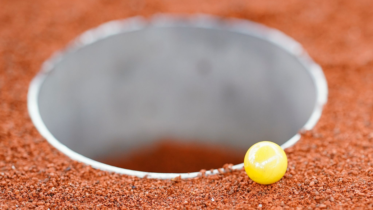Die Murmeln müssen in das Loch (eine Kuhle) auf dem drei Mal sechs Meter großen Feld befördert werden. - Foto: Uwe Anspach/dpa