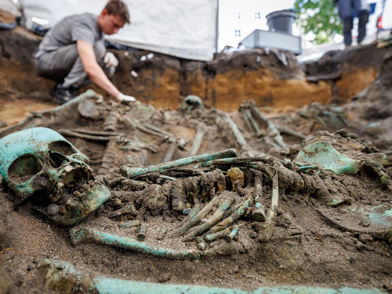 Bis zu eineinhalb Meter tief müssen die Fachleute graben, um alle Toten freizulegen.  - Foto: Daniel Karmann/dpa