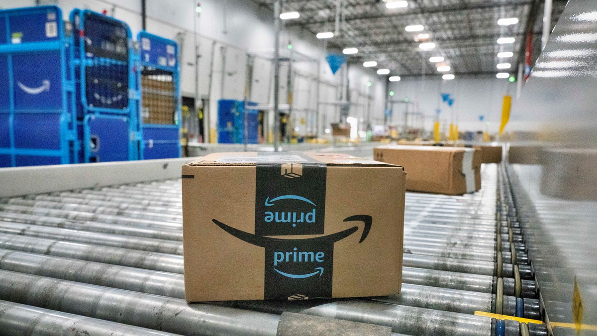 Ein Amazon-Paket auf dem Förderband einer Zustellstation - Foto: Richard Vogel/AP/dpa