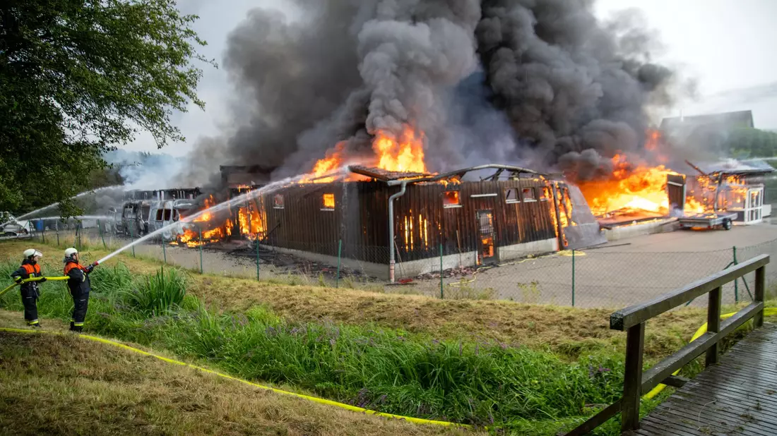 Einsatzkräfte löschen eine brennende Lagerhalle mit Fahrzeugen in Untermerzbach - Bild: Pia Bayer/dpa