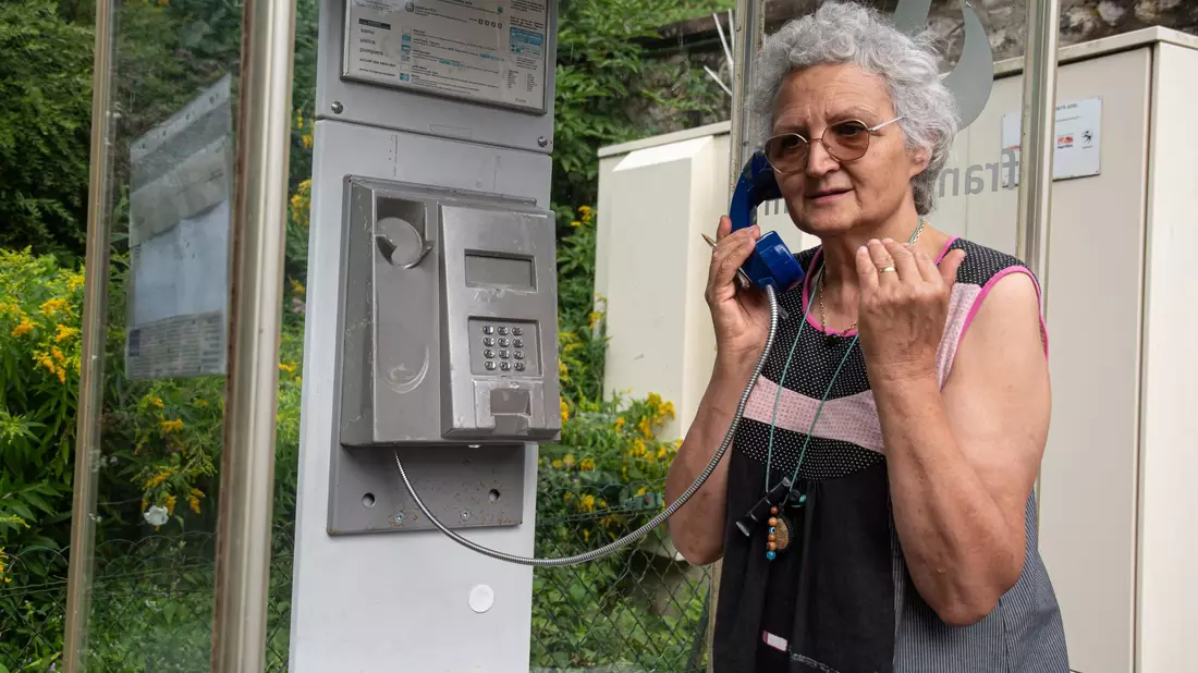 Marie-Claude König nimmt in Murbach einen Anruf entgegen. In der Telefonzelle im Elsass rufen Menschen aus der ganzen Welt an. - Bild: Florian Bodenmüller/SWD - Südwestdeutsches Mediennetzwerk GmbH/dpa