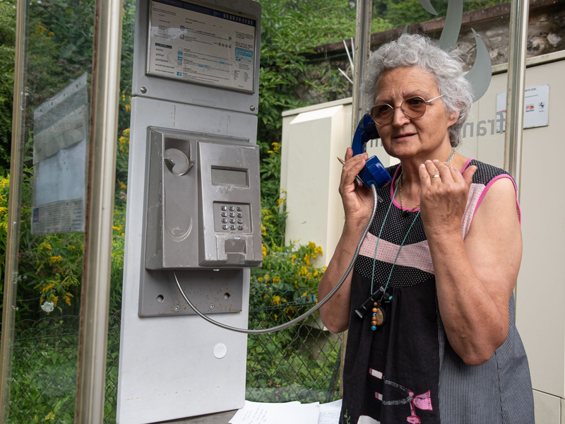 Marie-Claude König nimmt in Murbach einen Anruf entgegen. In der Telefonzelle im Elsass rufen Menschen aus der ganzen Welt an. - Foto: Florian Bodenmüller/SWD - Südwestdeutsches Mediennetzwerk GmbH/dpa