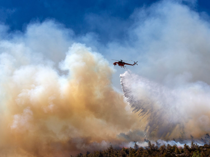 Noch immer flammen neue Brandherde auf, bekämpft wird auch aus der Luft. - Foto: Marios Lolos/XinHua/dpa