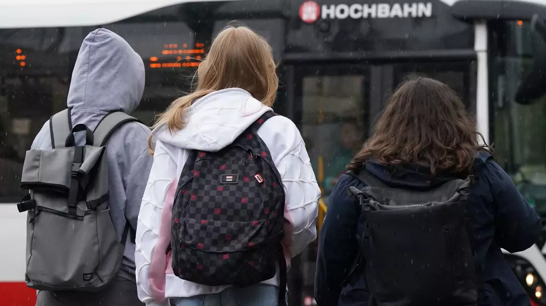 Zwei Schülerinnen und ein Schüler warten in Hamburg auf einen Bus. (Symbolbild) - Bild: Marcus Brandt/dpa