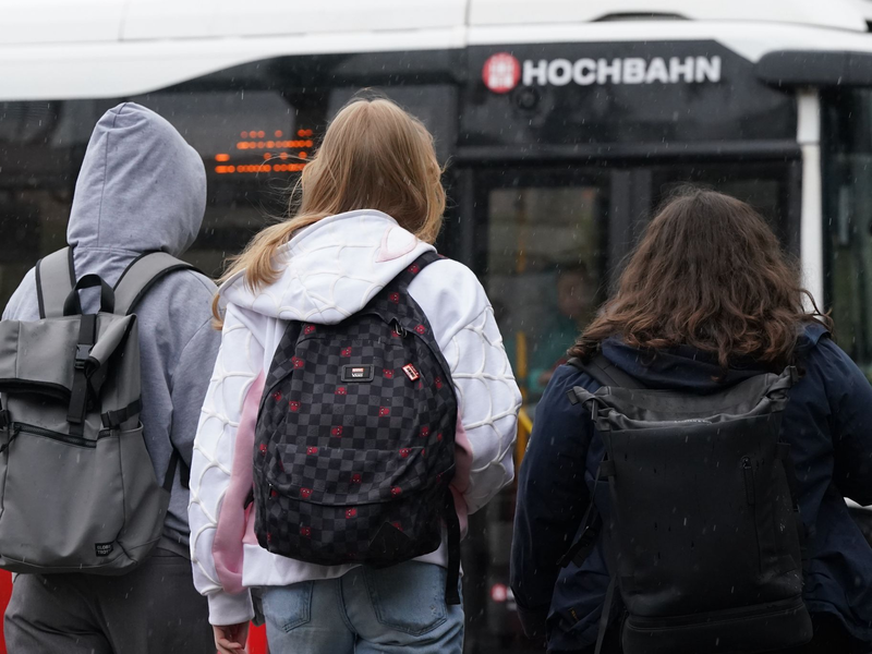 Zwei Schülerinnen und ein Schüler warten in Hamburg auf einen Bus. (Symbolbild) - Foto: Marcus Brandt/dpa