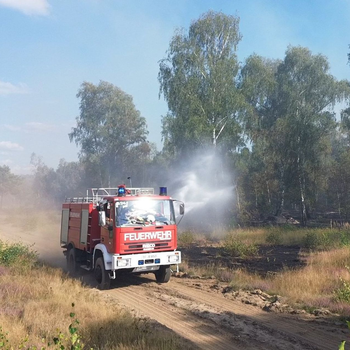 Die Feuerwehr löscht von Wegen aus beim Waldbrand in Jüterbog.  - Foto: Cevin Dettlaff/dpa